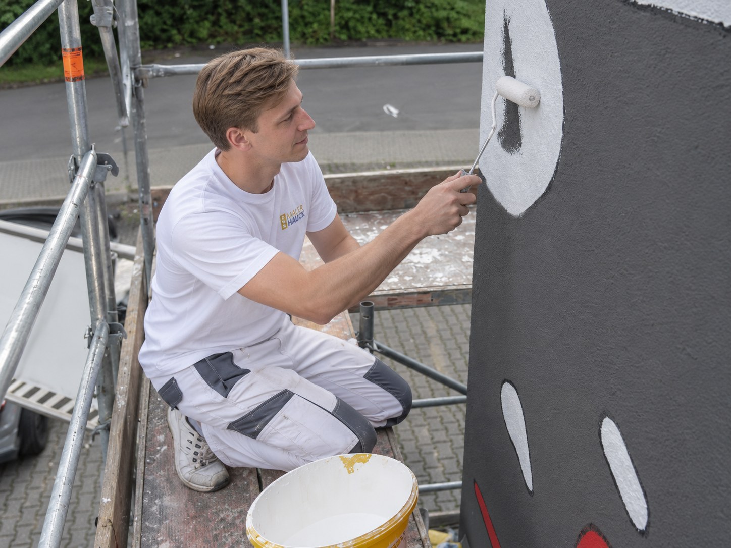 Maler streicht mit der Farbrolle ein Beschichtungsmuster auf eine Wand